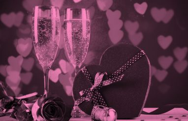 2香槟眼镜和一个心形盒巧克力,粉红色的过滤器